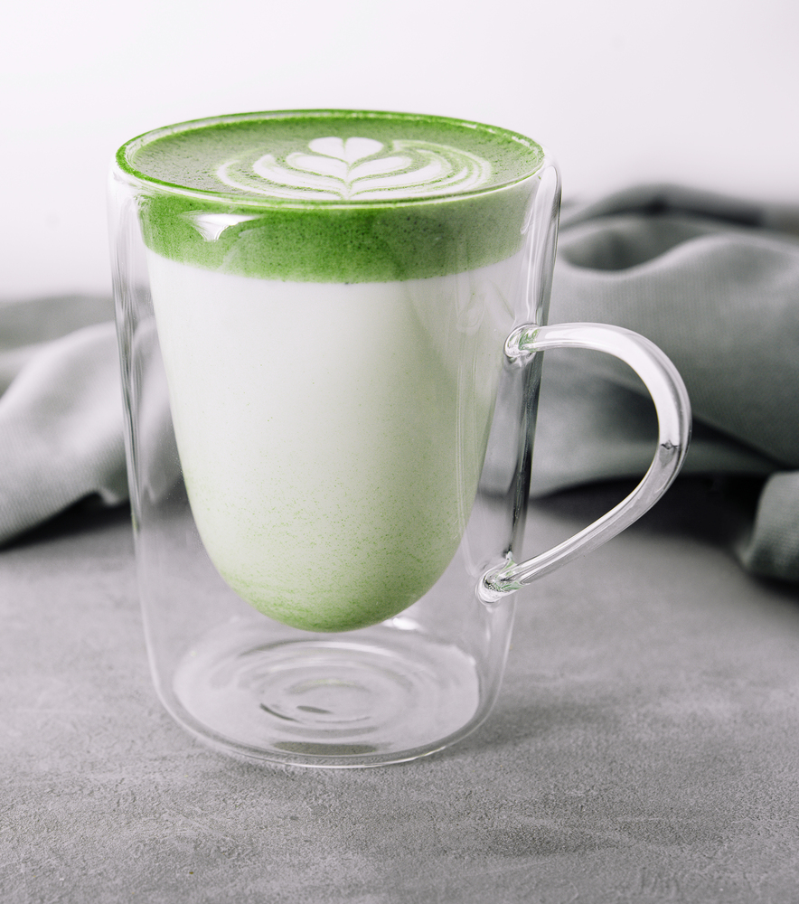 Glass of hot matcha green tea latte with oat milk